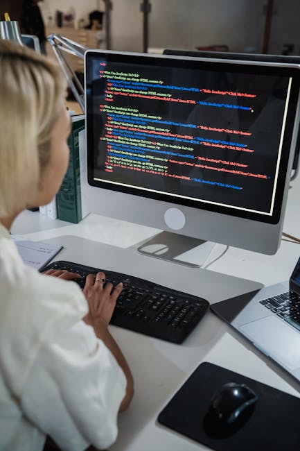 Person writing notes next to a laptop with code